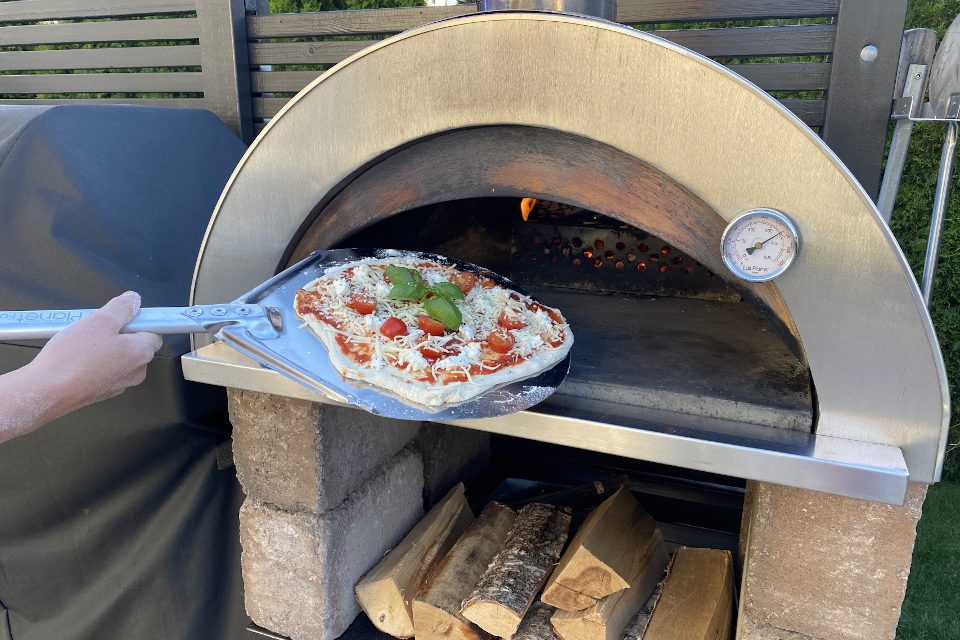 Legger pizza i varm ovn med spade